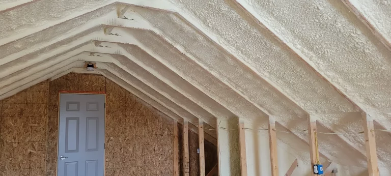 Professional spraying foam insulation on interior wooden wall studs in a building