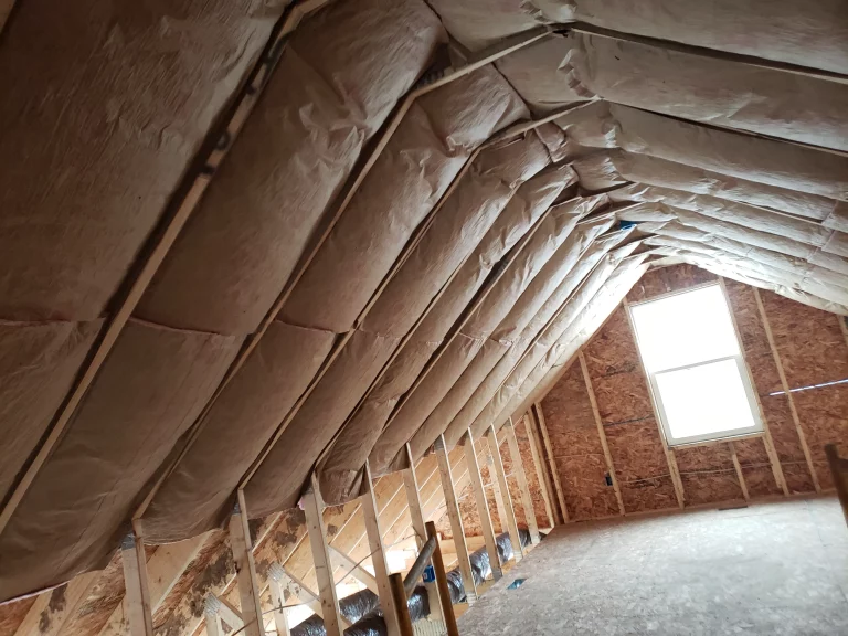 Attic wall with spray foam insulation and wooden framing.
