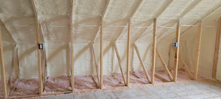 Attic wall with spray foam insulation and wooden framing.