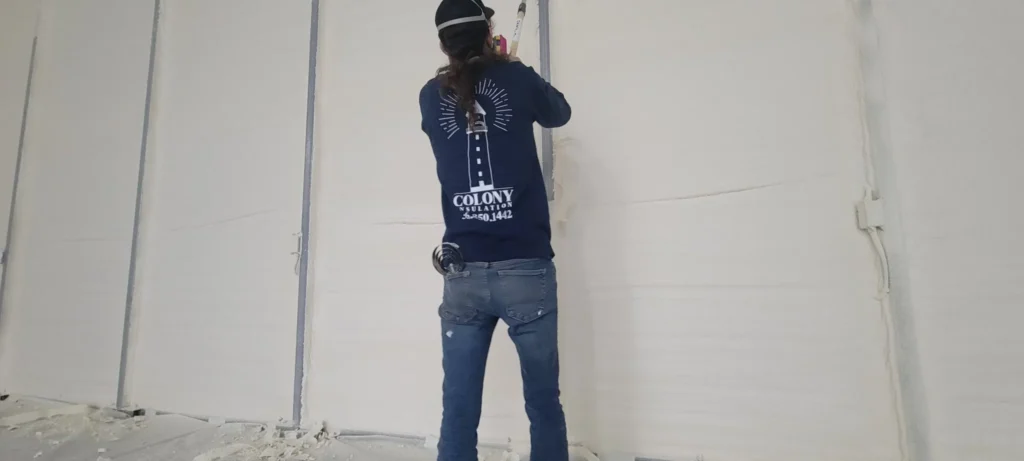 Colony Insulation technician installing closed-cell foam inside a commercial metal building to improve energy efficiency and air sealing