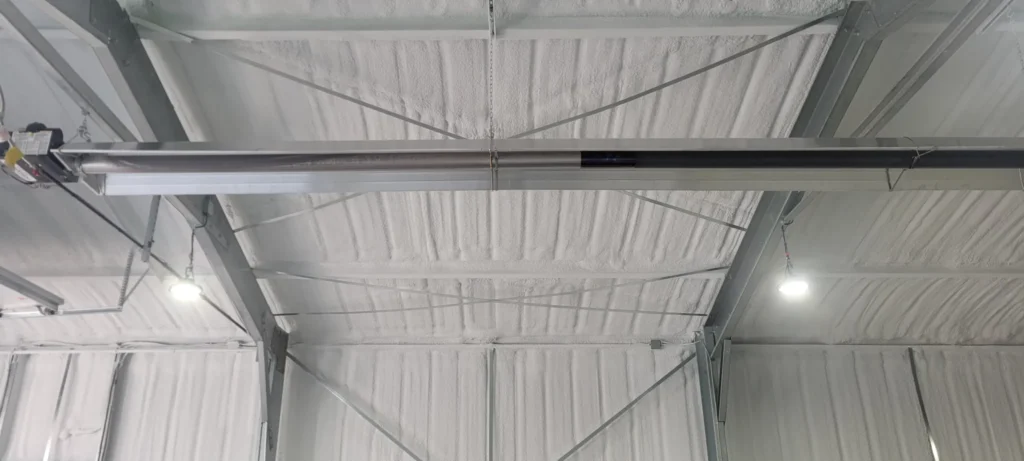 Closed-cell spray foam insulation applied to the underside of a metal building roof to improve energy efficiency and reduce air leakage