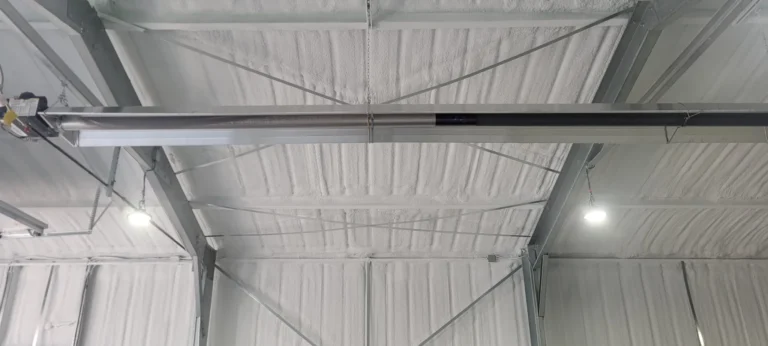 Closed-cell spray foam insulation applied to the underside of a metal building roof to improve energy efficiency and reduce air leakage