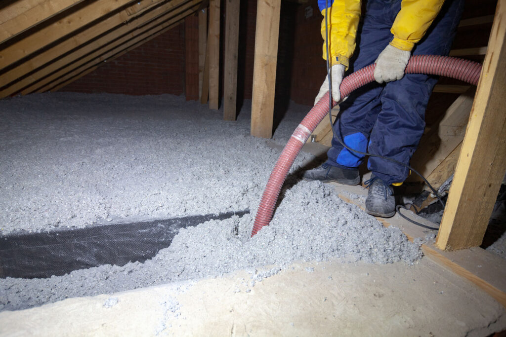 Technician installing blown-in insulation in an attic to improve energy efficiency and insulation coverage
