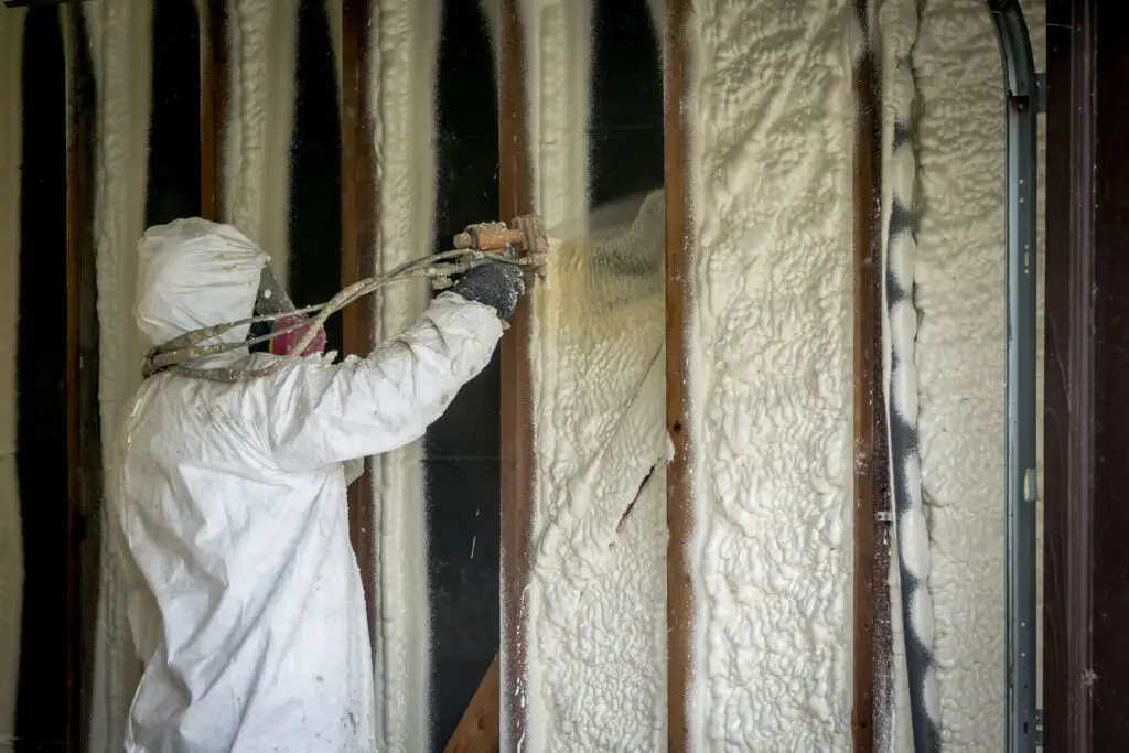 Technician installing spray foam insulation inside an exterior wall during a residential insulation project in Southeast Michigan